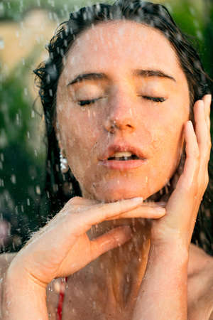 Beauty portrait of attractive woman with water drops of tropical shower. Spa procedures for hygiene careの写真素材
