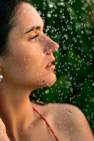 Girl washes under tropical rain shower. Summer vacation. Relaxation in spa. Skin and body careの写真素材