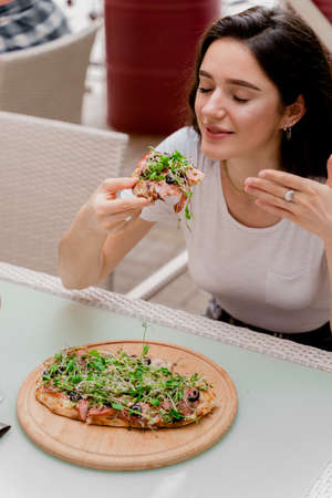 Girl with pinsa romana in cafe on summer terrace. Young woman eating pinsa and drinking wine.の写真素材