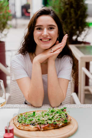 Girl with pinsa romana in cafe on summer terrace. Young woman eating pinsa and drinking wine.の写真素材