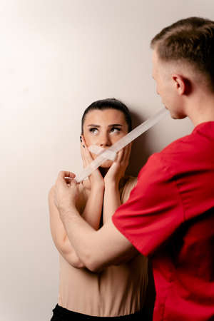 Model with glued mouth. Man covers woman mouth with tape. Stop talkingの写真素材