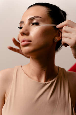 Facebuilding. Doctor with attractive female model. Blepharoplasty surgeryの写真素材