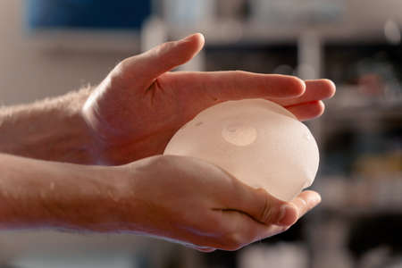 Silicone implant in hand close-up. Breast augmentation and lift surgery.の写真素材