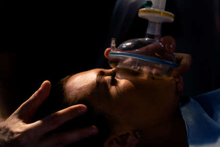 The doctor puts on a mask for artificial ventilation of the lungs in the intensive care unit.の写真素材