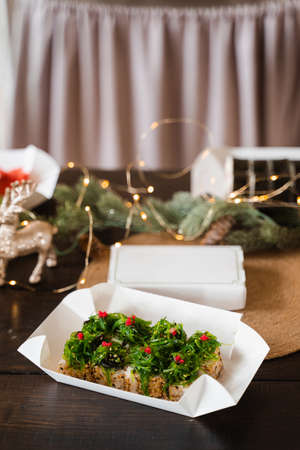 Sushi roll on the new year lights background. Christmas decoration. Food delivery at new year eve. Roll with chuka seaweedの写真素材