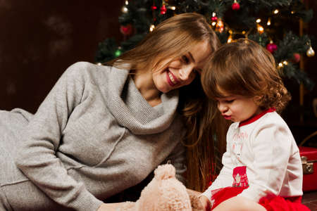 Mother and daughter preparing for christmas celebration. Having fun with family near new year tree....