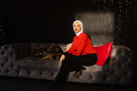Muslim woman near christmas lights and decoration in studio. Professional muslim model posing at the...