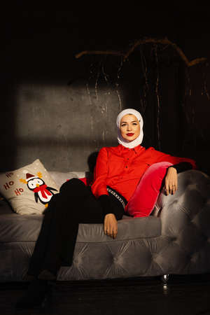 Muslim woman near christmas lights and decoration in studio. Professional muslim model posing at the...