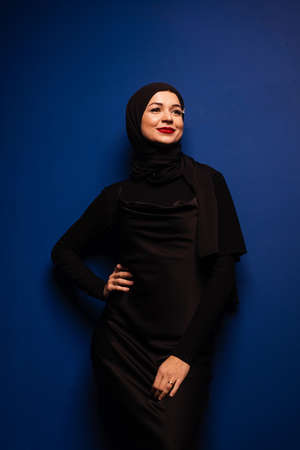 Fashion muslim model in black hijab is posing on blue background in studio. Islam religionの写真素材
