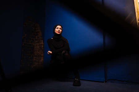 Fashion muslim model in black hijab is posing on blue background in studio. Islam religionの写真素材