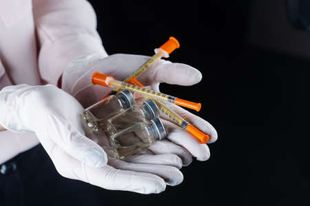 3 virus booster vaccines and syringes in hands in medical gloves. vaccination