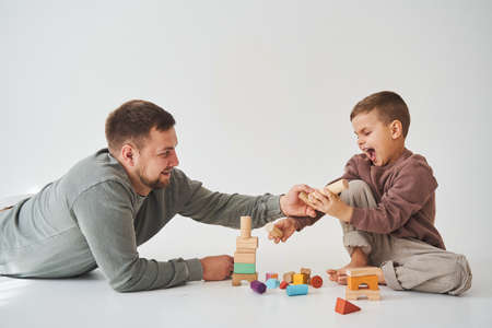 Dad and son smiling, having fun and playing colored bricks toy on white background. Paternity. Caring father with his childの写真素材