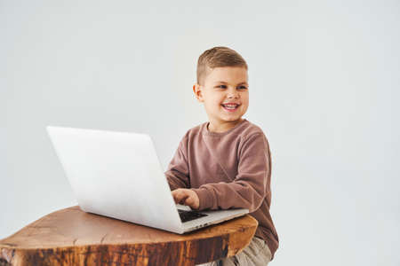 Gambling addiction. Handsome kid gamer is gaming on laptop on white background. Emotional child play...
