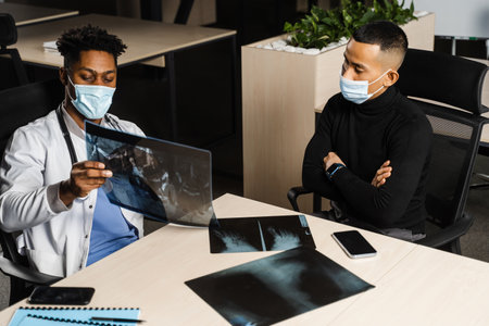 African doctor show x-ray asian patient. Black surgeon analyzing x ray and diagnosis patient in...
