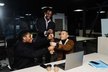 Teambuilding. Happy diverse business team of employees celebrating success. Teamwork achieve, making hand stack of fists. Community spirit and friendship. Keeping high motivationの写真素材