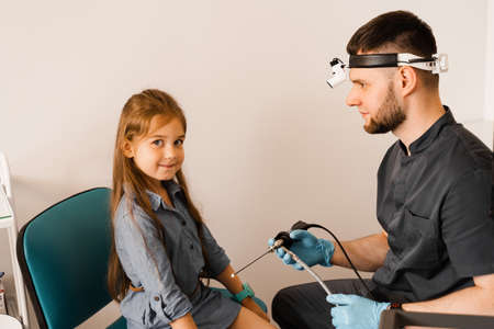 ENT doctor otolaryngologist with headlight showing to child endoscope for rhinoscopy and otoscopy. Nose and ears endoscopy of childの写真素材