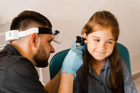 Otoscopy of child ears with otoscope. ENT doctor. Consultation with pediatric otolaryngologist. Treatment of childs ear painの写真素材