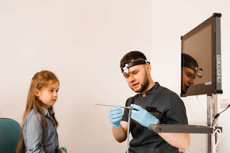 ENT doctor otolaryngologist with headlight showing to child endoscope for rhinoscopy and otoscopy. Nose and ears endoscopy of childの写真素材