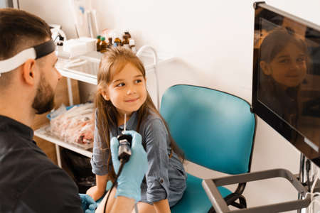 Nose endoscopy of child. Rhinoscopy procedure with rhinoscope. ENT doctor otolaryngologist with headlight treat nose kid patientの写真素材