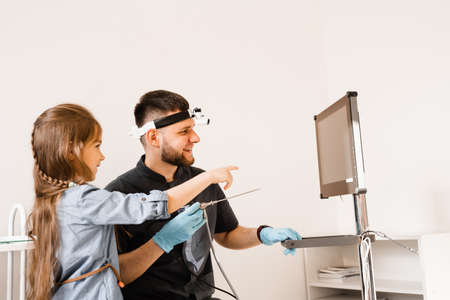 ENT doctor otolaryngologist with headlight showing to child endoscope for rhinoscopy and otoscopy. Nose and ears endoscopy of childの写真素材