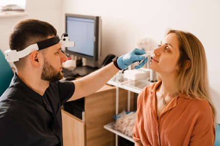Rhinoscopy of woman nose. Consultation with doctor. Otolaryngologist examines girl nose before procedure of endoscopy of noseの写真素材