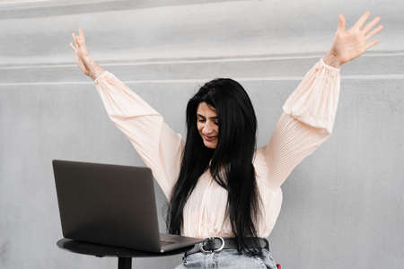 Attractive woman with laptop and headphones working online on remote work and listen music. Adorable georgian girl enjoy her life with listening music and chatting with friendsの写真素材