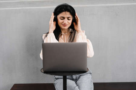 Attractive dj woman with laptop and headphones mixing music on and listen new composition. Adorable georgian girl enjoy her life with listening music and chatting with friendsの写真素材