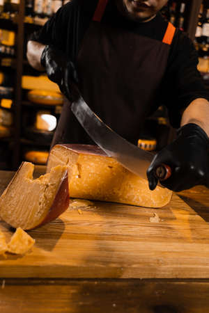 Cheese sommelier cutting limited gouda cheese with knife. Snack tasty piece of cheese for appetizer