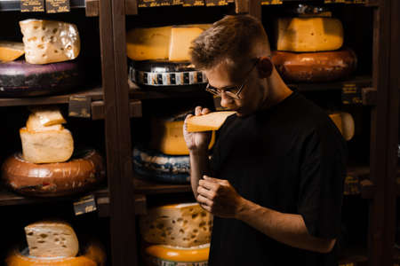 Handsome buyer in cheese shop sniff and enjoy limited gouda cheese. Snack tasty piece of cheese for...