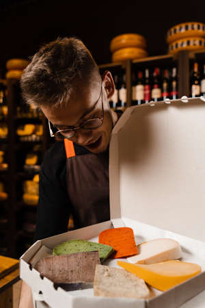 Surprised cheese sommelier with mix of young Gouda, young goat, lavander cheese and green and red...
