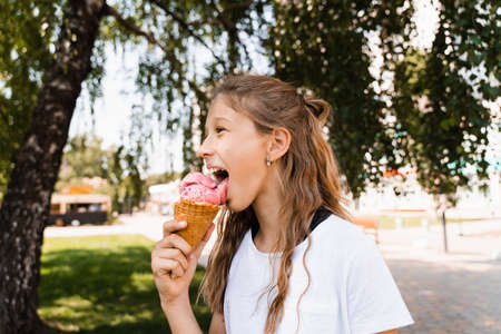 Funny child girl eating ice cream cone in waffle cup. Creative advert for ice cream stand and shop