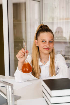 Chemistry lesson at school. Girl with flask is studying in chemistry classroom. Schoolgirl holding flask with chemical in the laboratoryの写真素材