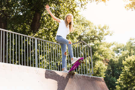 Teenager girl with penny board ready to go down on skateboard park playground. Sport equipment....