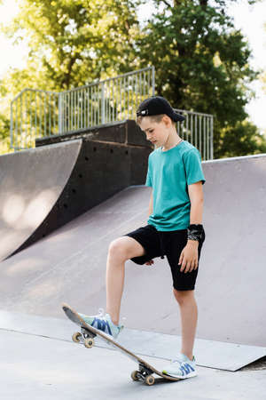 Teenager boy ready for ride on skate board on skateboard park playground. Sports equipment for kids. Extreme lifestyleの写真素材