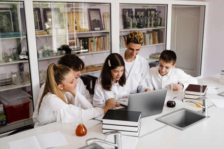 The class is studying in the chemistry lesson at school in the laboratory. Education. The teacher checks the homework in the book. Preparing for experimentsの写真素材