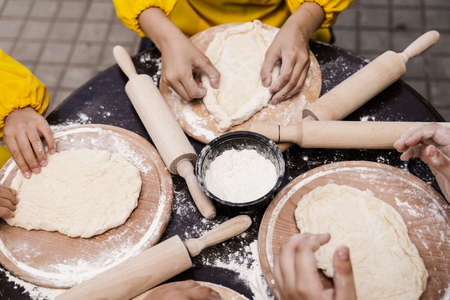Multinational company of children cooks cooking dough close-up. Young cooks children cooking khachapuriの写真素材