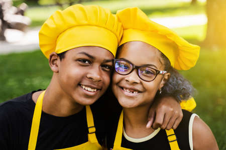 African children cooks in chefs hat and yellow uniforms smiling close-up portrait . African teenager and black girl have fun and cook foodの写真素材