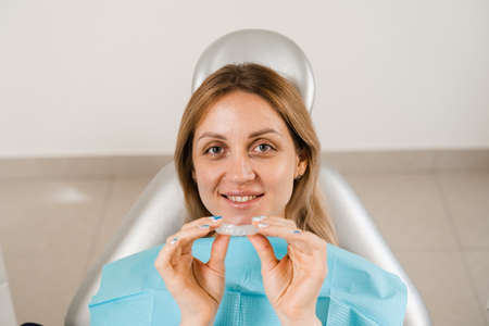 Orthodontist shows mouth guard for teeth whitening in dentistry. Dentist consult woman patient about...
