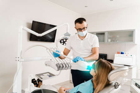 UV teeth whitening for woman patient in protective glasses in dentistry. Laser bleaching teeth in...
