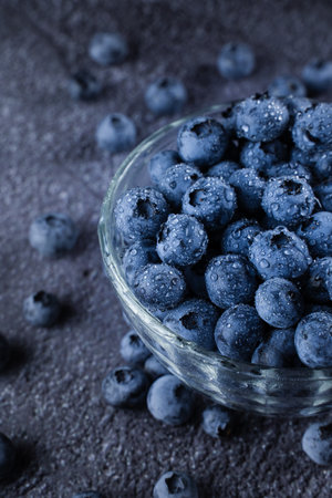 Blueberry in glass bowl plate. Blueberries natural organic berry with water drops on dark backgroundの写真素材