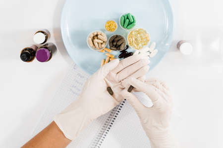 Nutritionist holding biologically active supplements tablets in gloves and help patient to plan daily diet. Pills for weight loss. Recommendation for daily dietaryの写真素材