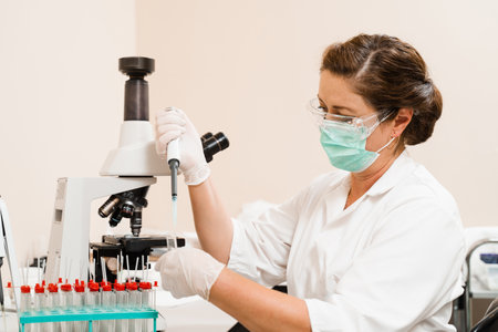 Laboratory assistant with dispenser in laboratory doing blood test analysis. Medical equipment in...