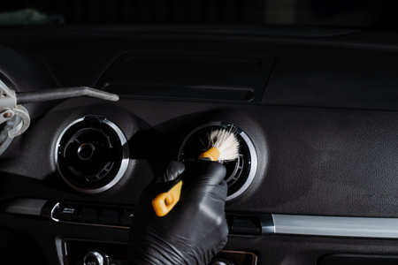 Cleaning with air and brush of air conditioning system in the car. Worker in detailing auto service clean elements of interior of carの写真素材