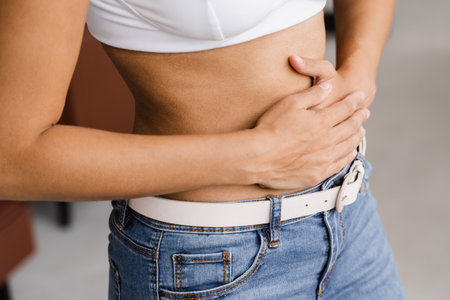 Stomach pain. Sick african american girl hold abdomen because it hurts. Pancreatitis disease of pancreas becomes inflamedの写真素材