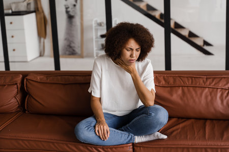 Laryngitis first symptoms throat ache. Sick african american girl touches throat with pain. Seasonal illness medecineの写真素材