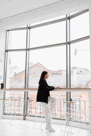 Smart girl student with laptop study english online at linguistic school in white cafe. Attractive young woman have video communication lesson with teacherの写真素材