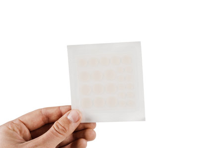 Set of round patches for acne in hand on white background. Top view of acne patch for facial rejuvenation. Facial cleansing cosmetologyの写真素材
