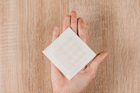 Set of round patches for acne on hand on wooden background. Facial cleansing cosmetology. Top view...