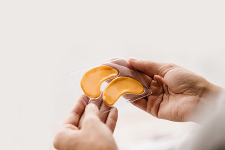 Close-up set of gold pathes for smooth out fine wrinkles, remove swelling or bags under the eyes. Golden hydrogel eye patches with peptides and hyaluronic acid in handsの写真素材