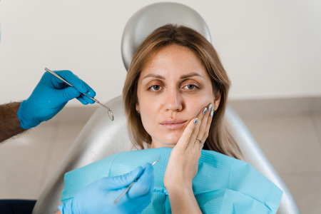 Strong toothache in woman. Upset girl with teeth ache. Consultation and treatment caries in dentistry. Dentist examines patient girlの写真素材